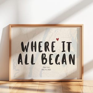Może przedstawiać: Oprawiony wydruk z czarnym napisem "WHERE IT ALL BEGAN" na mapie Nowego Jorku. Małe czerwone serce znajduje się nad słowem "IT". Widoczne są również napisy "New York" i "May 16, 2023".