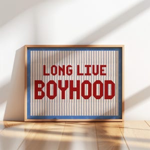 May include: A framed print with a blue and white striped background and the text "Long Live Boyhood" in red.