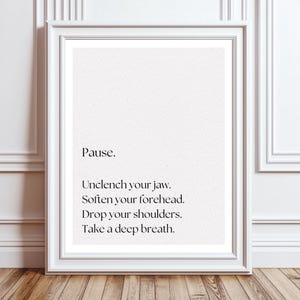 May include: A white framed print with black text that reads: "Pause. Unclench your jaw. Soften your forehead. Drop your shoulders. Take a deep breath."