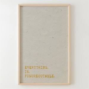May include: A framed print with a white background and a gold inscription that reads "EVERYTHING. IS. FIGUREOUTABLE."