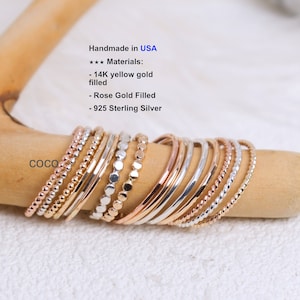 May include: A set of 10 delicate stacking rings in gold, rose gold, and silver. The rings are made of 14K yellow gold filled, rose gold filled, and 925 sterling silver. Handmade in the USA.