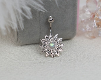 May include: A silver belly button ring with a clear opal gemstone in the center and a silver flower design with clear rhinestones around the opal.