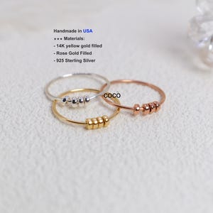 May include: Three delicate rings in silver, gold, and rose gold, each adorned with small, evenly spaced beads. The rings are handmade in the USA and are made of 14K yellow gold filled, rose gold filled, and 925 sterling silver.