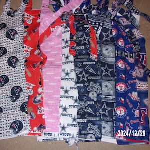 May include: Assorted aprons with various patterns, including the Houston Texans logo, Mickey Mouse, pink stripes, and Dallas Cowboys logos. The aprons are made of fabric and have neck and waist ties. The date 2024/12/29 is visible.