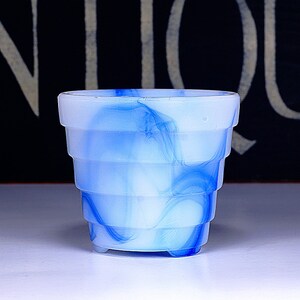 May include: A white and blue swirl glass planter with a fluted design. The planter has a blue and white marbled pattern.