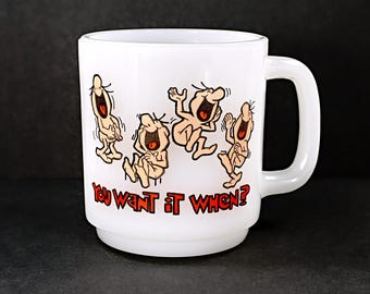 May include: White ceramic coffee mug with a cartoon image of five people laughing. The mug has the text "You want it when?" printed on the front.