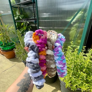 May include: Five crocheted yarn toys in different colours, including white, grey, pink, orange, and brown. Each toy has a face with two googly eyes.