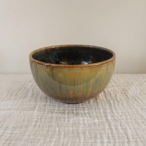 May include: A ceramic bowl with a dark brown interior and a green and brown glaze on the exterior.