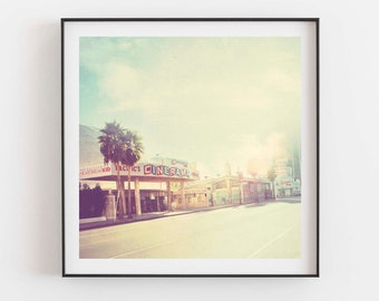 May include: A vintage photograph of a street scene with palm trees and a building with the word "CINEMA" on the front. The photo has a faded, retro look.