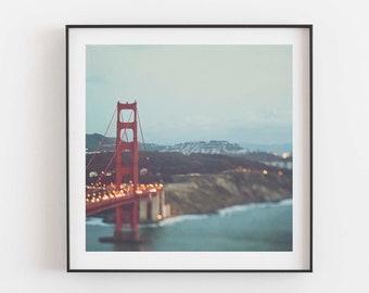 May include: A framed photograph of the Golden Gate Bridge in San Francisco, California. The bridge is red and is seen from a distance, with the city skyline in the background.