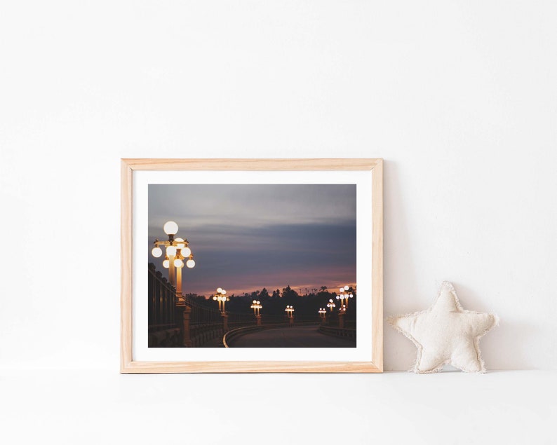 May include: A framed photograph of a bridge at dusk with streetlights illuminating the road. The sky is a gradient of purple, pink, and blue.