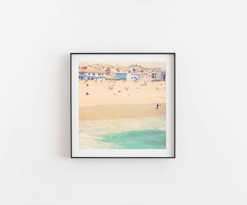 K&ouml;nnte beinhalten: Ein Vintage-Foto einer Strandszene mit bunten H&auml;usern im Hintergrund, einem Sandstrand und einer Person, die im Meer surft.