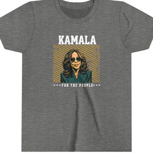 May include: A gray t-shirt with a graphic of Kamala Harris, a woman with dark hair and sunglasses, with the text "Kamala" and "For the People" in yellow.
