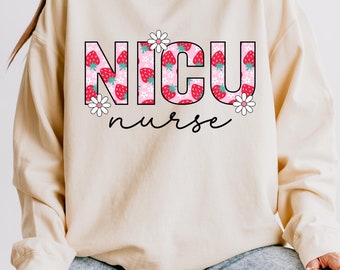 May include: A cream-coloured sweatshirt featuring the words "NICU nurse". The letters are decorated with a strawberry pattern and white daisy accents. The word "nurse" is written in a cursive font.