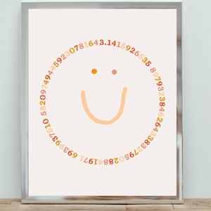 May include: A white framed print with a peach and orange smiley face made of numbers in a circle. The numbers are in a circular pattern and are in different shades of peach, orange, and brown.
