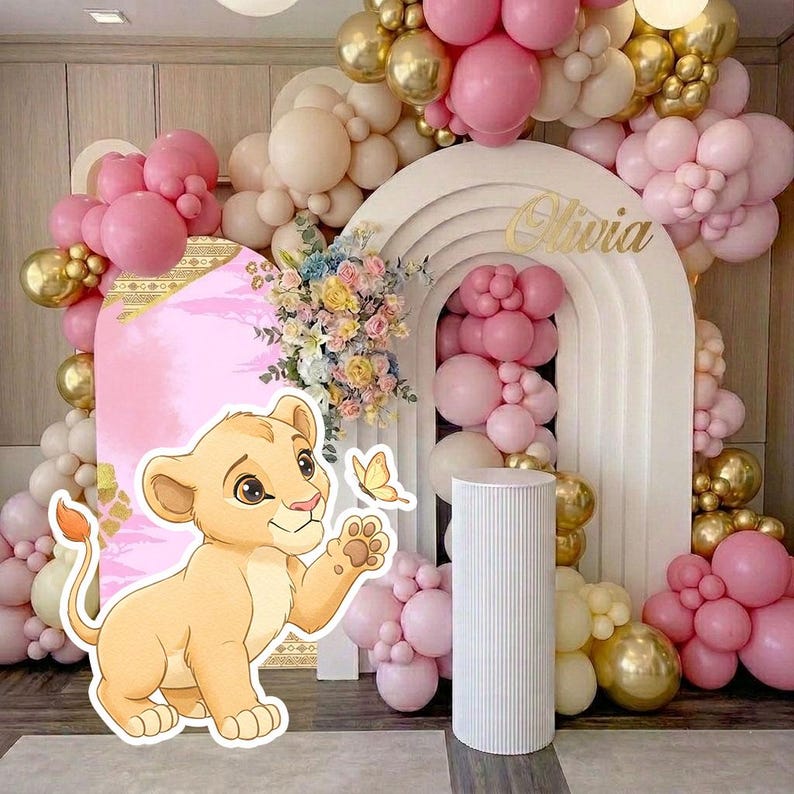 May include: A party backdrop featuring a cartoon lion cub, pink and gold balloons, and a white arch with the name "Olivia" in gold. The backdrop includes a pink panel with floral arrangements and a butterfly.