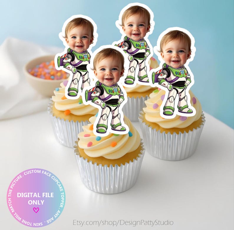 May include: Four cupcakes in silver foil liners topped with white frosting and colourful sprinkles. Each cupcake features a custom paper topper showing a baby's face superimposed onto a cartoon space ranger suit with green, purple, and white details.