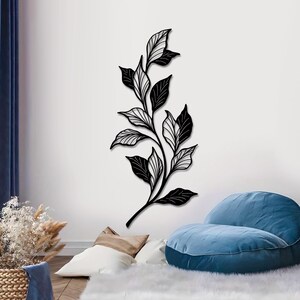 May include: Black metal wall art featuring a stylized branch with leaves. The leaves are detailed with intricate lines and have a black and white color scheme.