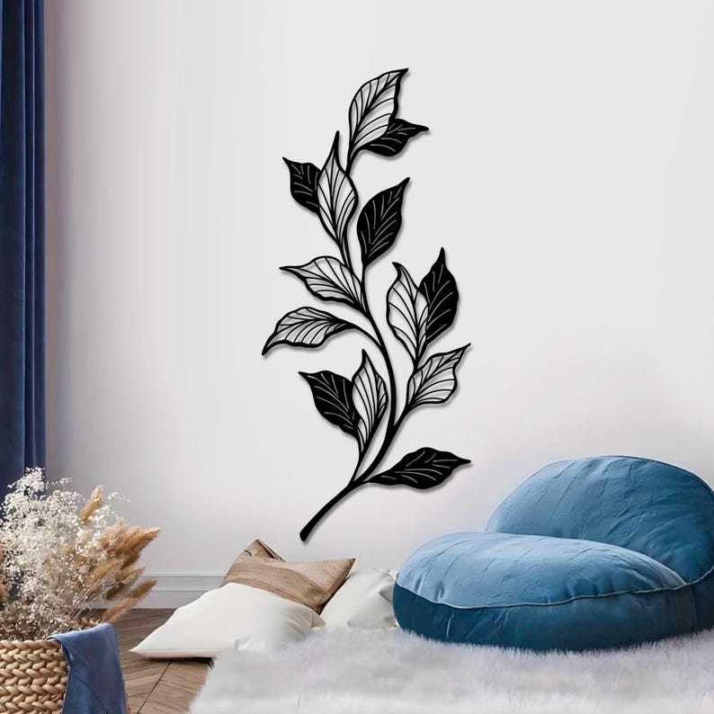 May include: Black metal wall art featuring a stylized branch with leaves. The leaves are detailed with intricate lines and have a black and white color scheme.