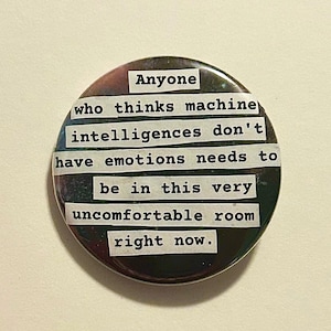 May include: A circular badge with a dark, mottled background and white text. The text says: "Anyone who thinks machine intelligences don't have emotions needs to be in this very uncomfortable room right now."
