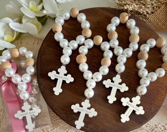 May include: Four white pearl and wooden bead rosaries with silver cross charms. The crosses are engraved with the names "Baptism Day", "Laurelle Marie", and "Laurelle Marie".