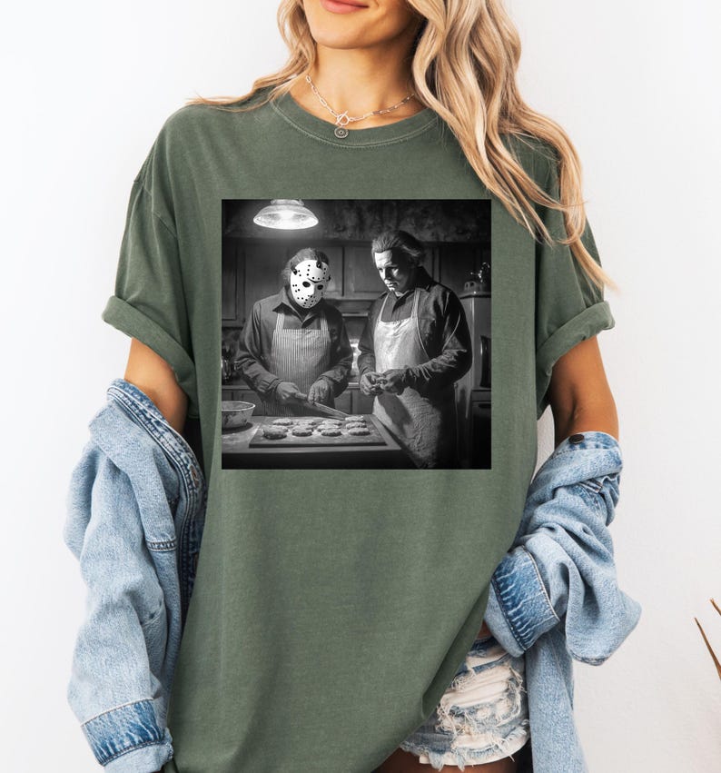 Puede incluir: Camiseta verde con una imagen en blanco y negro de dos figuras con delantales, una de ellas con una m&aacute;scara de hockey, horneando en una cocina. La imagen est&aacute; centrada en la camiseta, ofreciendo un dise&ntilde;o &uacute;nico y tem&aacute;tico. La camiseta es c&oacute;moda e informal.