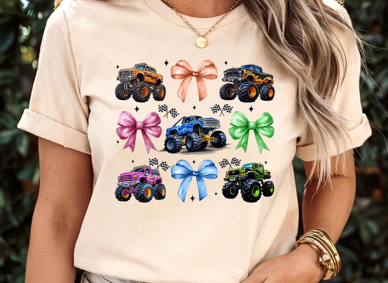 Puede incluir: Camiseta beige con un dise&ntilde;o de seis monster trucks coloridos y seis lazos en tonos rosa, naranja, azul y verde. Cada cami&oacute;n tiene neum&aacute;ticos grandes y est&aacute; decorado con banderas de carreras.