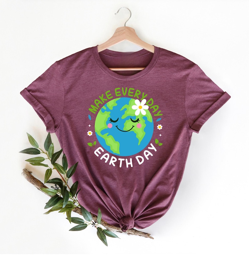 May include: A maroon t-shirt with a graphic of a smiling cartoon Earth with a daisy on top. The text "Make Every Day Earth Day" surrounds the Earth.