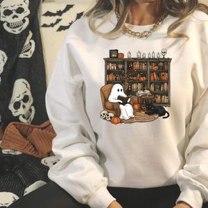 a woman sitting on a couch wearing a ghost sweatshirt