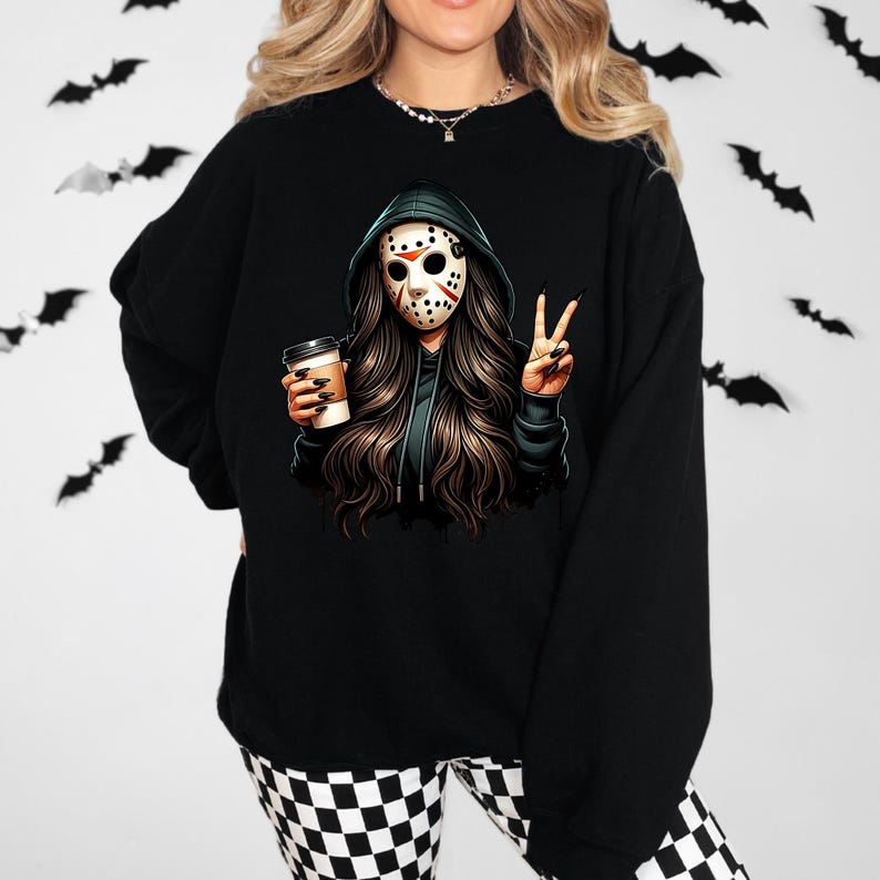 May include: Black sweatshirt with a graphic of a person in a hockey mask and green hoodie, holding a coffee cup and making a peace sign. The design has long brown hair. The background has bat silhouettes.