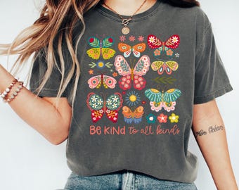 May include: A dark gray t-shirt with a colorful butterfly design and the text "Be Kind to all kinds".