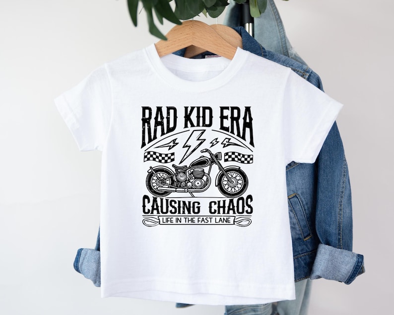 May include: White t-shirt with a black graphic of a motorcycle and the text "Rad Kid Era Causing Chaos Life in the Fast Lane"