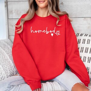 May include: Red sweatshirt with the text "homebody" in white with a small white heart.