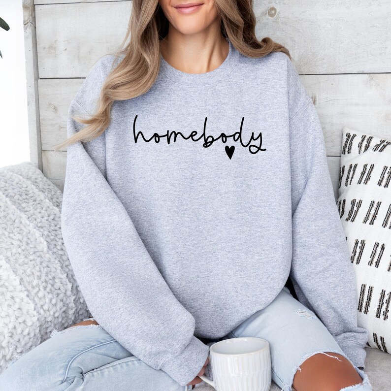 May include: A grey sweatshirt with the text "homebody" and a small heart in black.