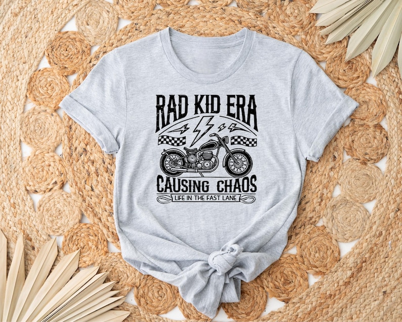 May include: Grey t-shirt with a black and white graphic of a motorcycle and the text "Rad Kid Era Causing Chaos Life in the Fast Lane"
