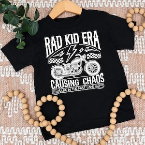 May include: Black t-shirt with a white graphic of a motorcycle and the text "Rad Kid Era Causing Chaos Life in the Fast Lane"