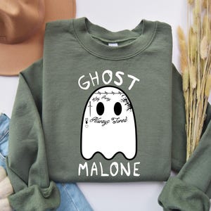 May include: A green sweatshirt with a white ghost graphic and the text "Ghost Malone" with the words "Stay F*ncy Always Tired" inside the ghost.