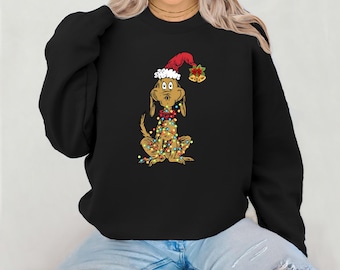 May include: Black sweatshirt with a graphic of a brown dog wearing a Santa hat and Christmas lights. The dog is sitting down and has a surprised expression on its face.