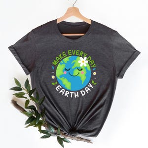 May include: A dark gray t-shirt with a graphic of a smiling cartoon Earth with a flower on top. The text "Make Every Day Earth Day" surrounds the Earth graphic.