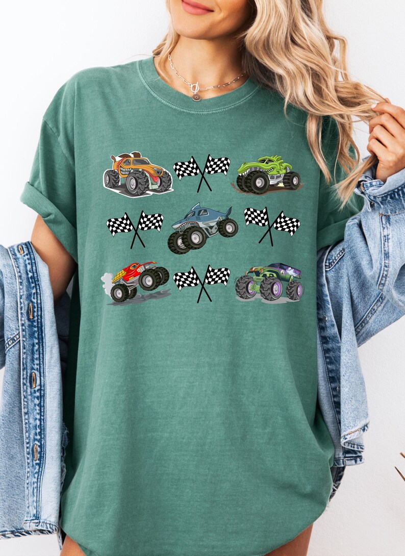 Pode incluir: Camiseta verde com gr&aacute;ficos coloridos de monster trucks e bandeiras quadriculadas. Os caminh&otilde;es s&atilde;o de v&aacute;rias cores, incluindo laranja, verde, azul e roxo. O design &eacute; divertido e adequado para os f&atilde;s de monster trucks.