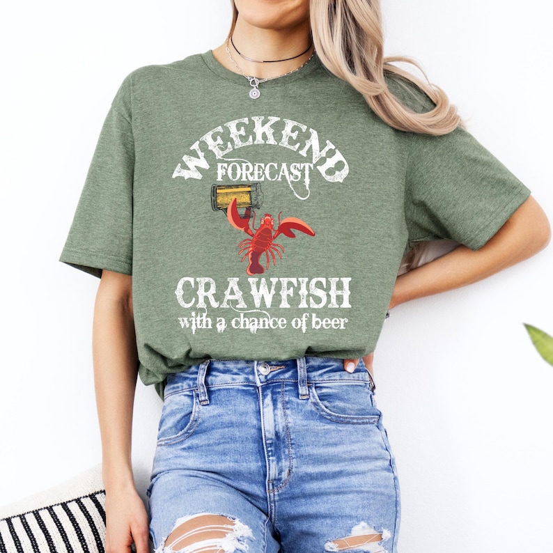 May include: Green t-shirt with a white graphic that says "Weekend Forecast Crawfish with a chance of beer". The graphic also includes a cartoon crawfish holding a beer.