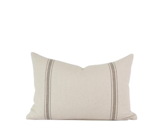 May include: A white pillow with two brown stripes down the center. The pillow is made of a soft, textured fabric.