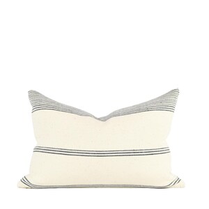 May include: A white pillow with black stripes. The pillow is made of a soft, woven fabric.