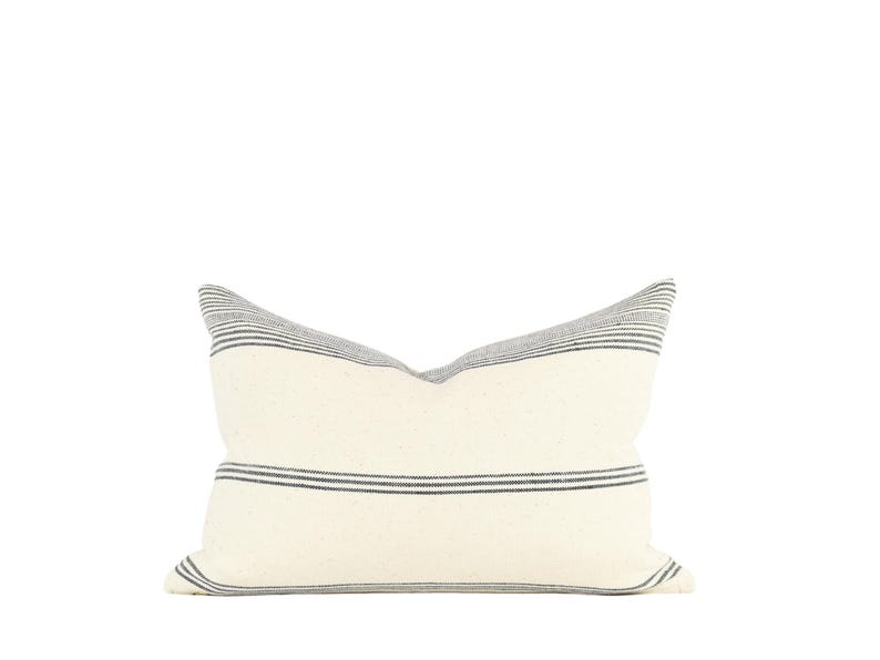 May include: A white pillow with black stripes. The pillow is made of a soft, woven fabric.