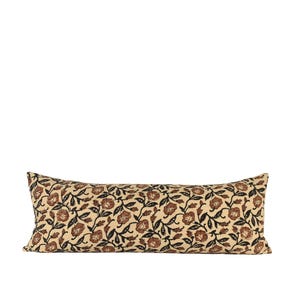 Puede incluir: Un cojín rectangular decorativo con un estampado floral. El cojín presenta un fondo color crema con un diseño repetido de flores marrones y hojas negras. El cojín está diseñado para uso decorativo.