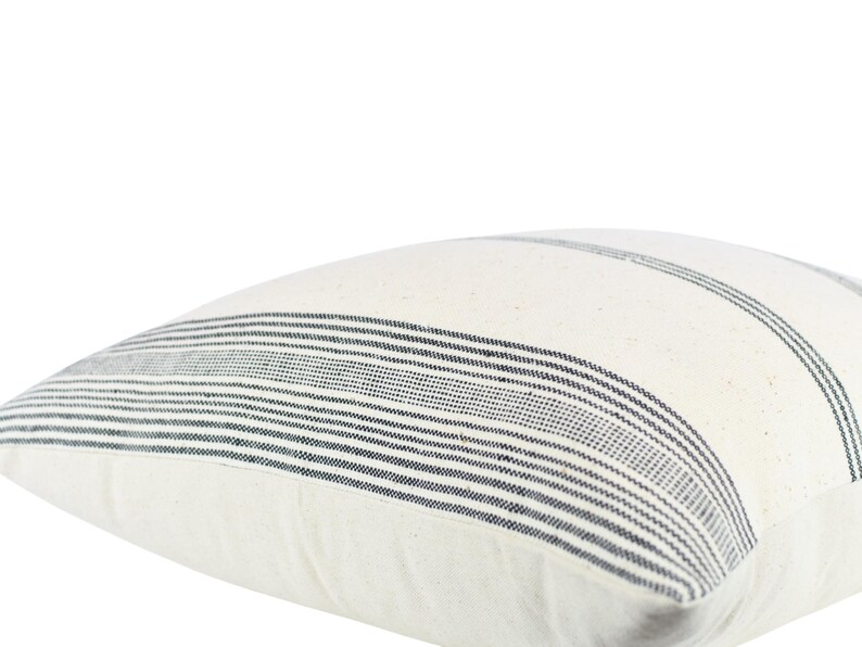 May include: White pillow cover with black stripes. The pillow cover is made of a soft, woven fabric.