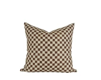 May include: A brown and cream checkered throw pillow with a square pattern.