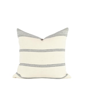 May include: A white pillow with black stripes. The pillow is made of a soft, textured fabric.