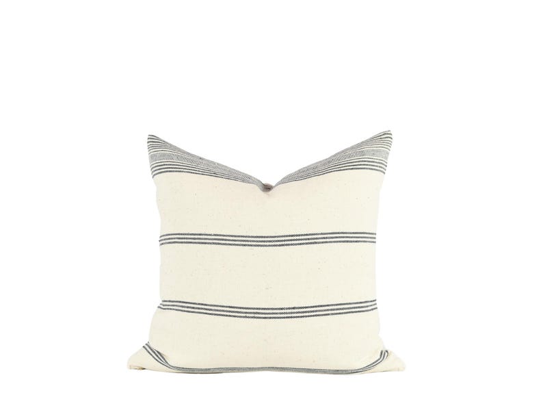 May include: A white pillow with black stripes. The pillow is made of a soft, textured fabric.