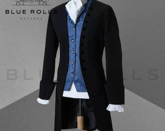 May include: A black long coat with a blue patterned vest and a white shirt. The coat has a long tail and is buttoned up the front. The vest has a gold button closure. The shirt has a white collar and a white cravat.